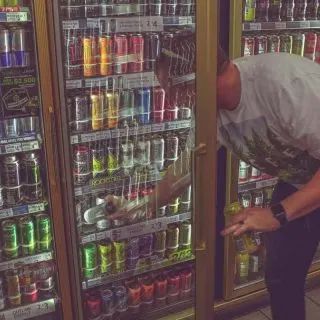 A man buying energy drink in a convenience store.