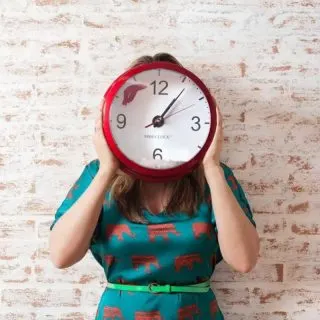 A picture of woman holding a wallclock.