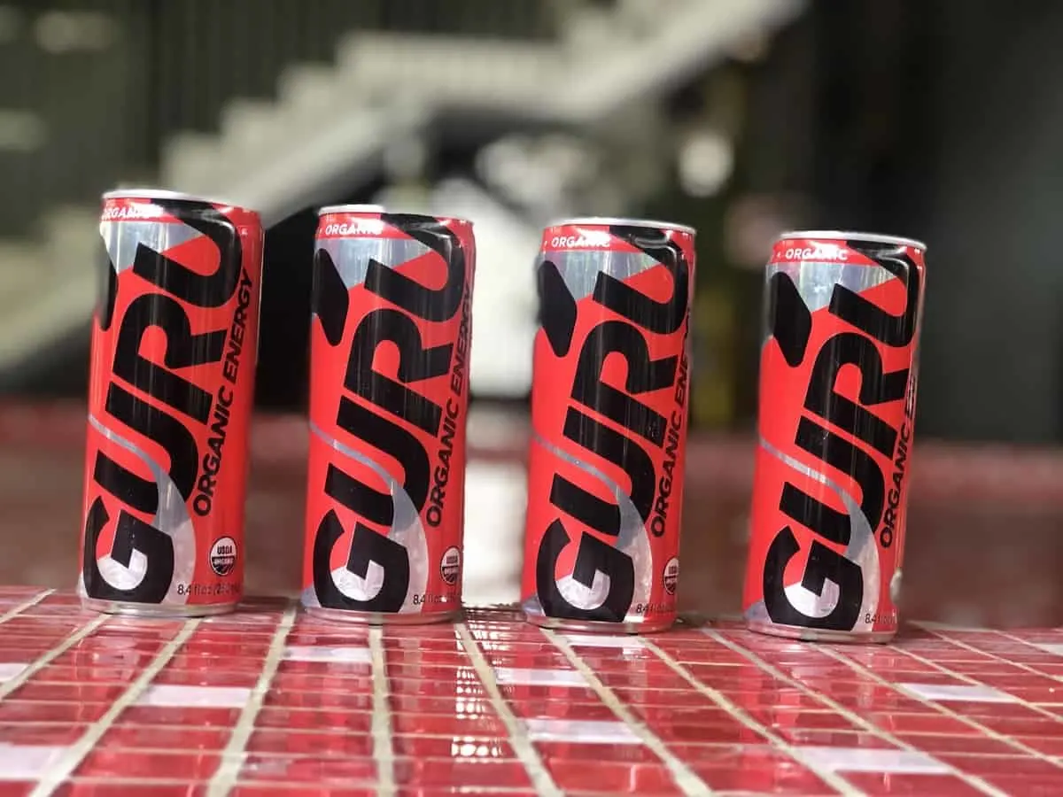 A picture of 4 cans of Guru energy drink in a red floor.