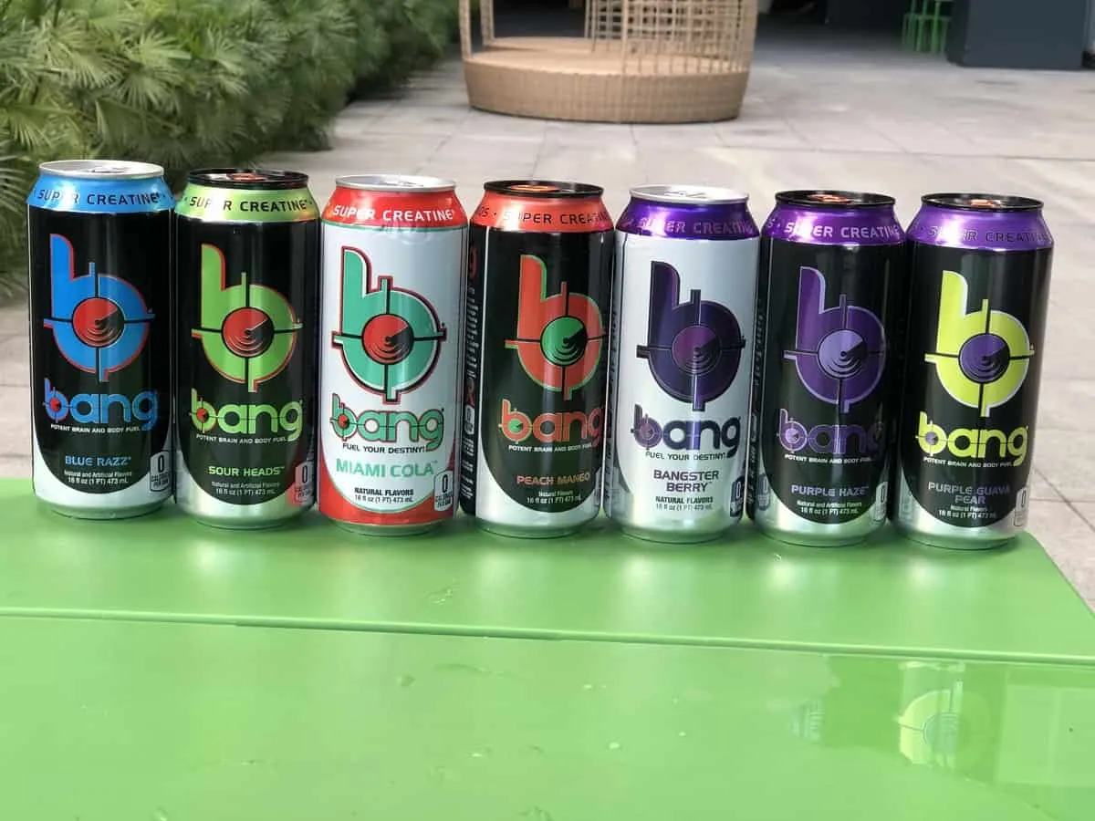 7 cans of Bang energy flavors in a green table.