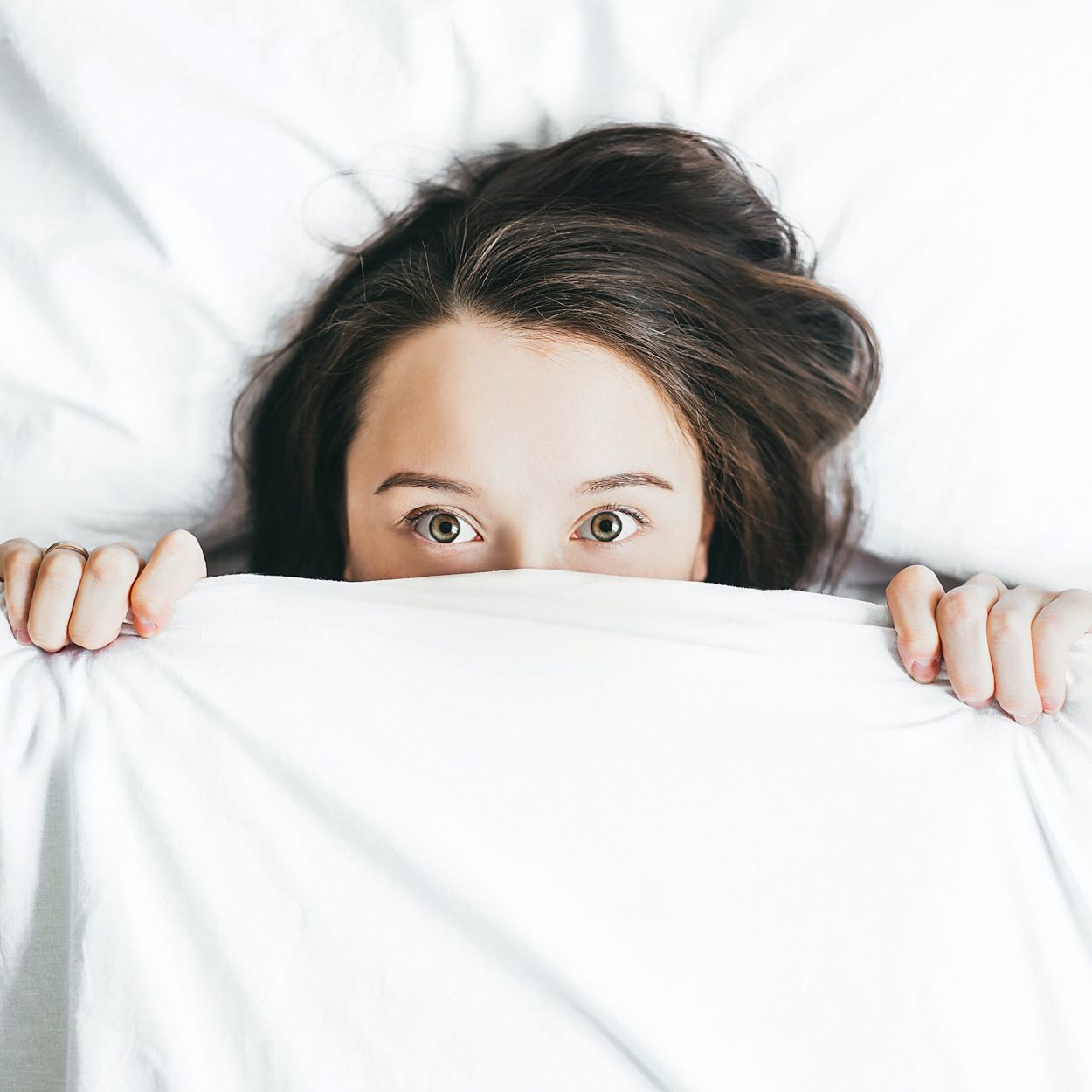 A woman has hidden her face with a white bedsheet