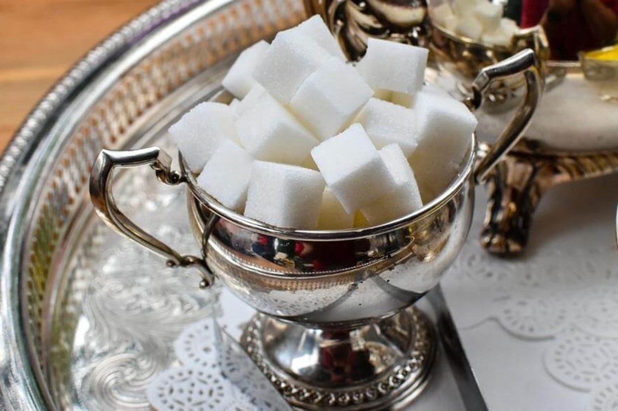 An image of a sugar pot containing sugar cubes placed in a tray