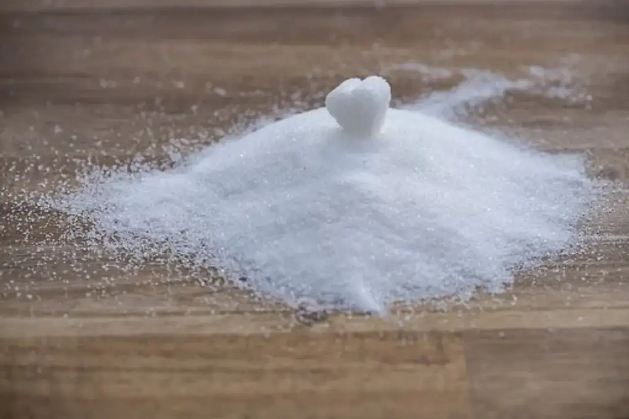 A heart shape forming at the middle of scattered sugar. 