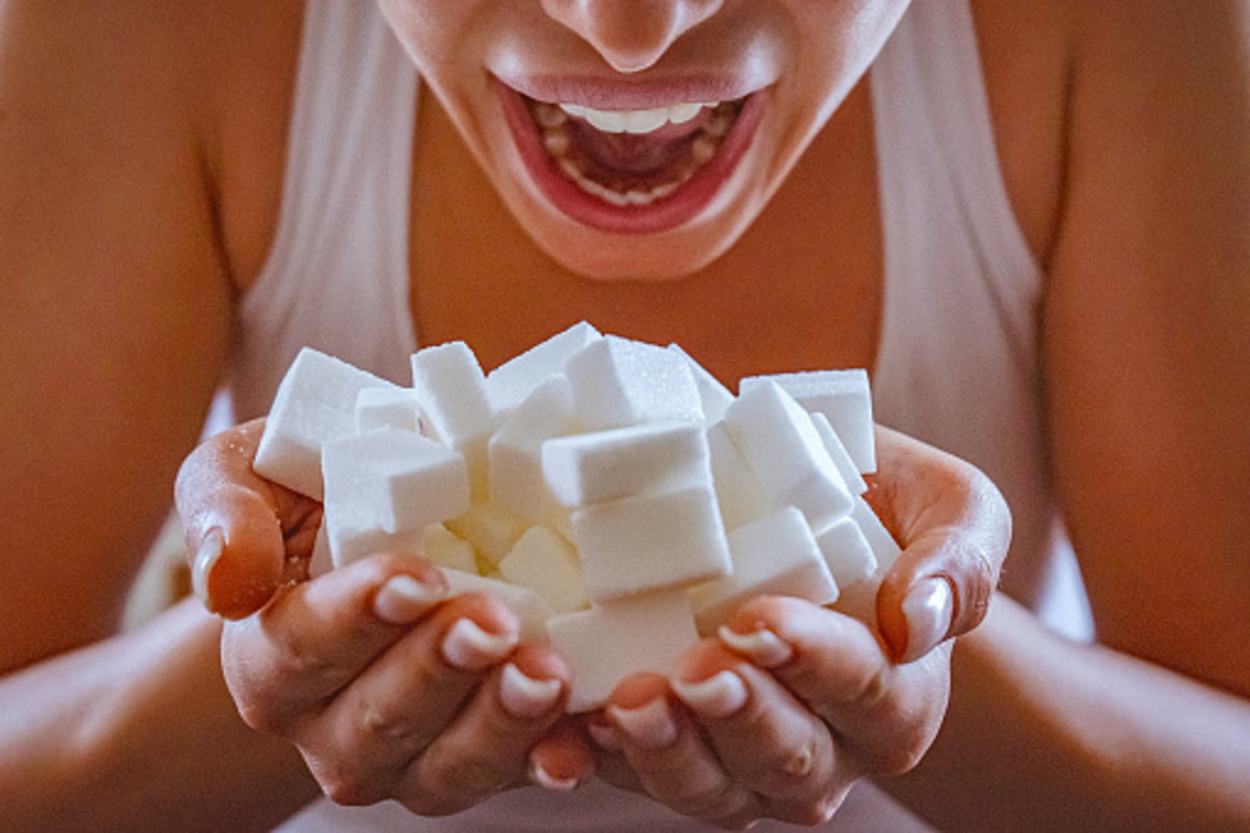 Woman sugar cubes in front of her open mouth.