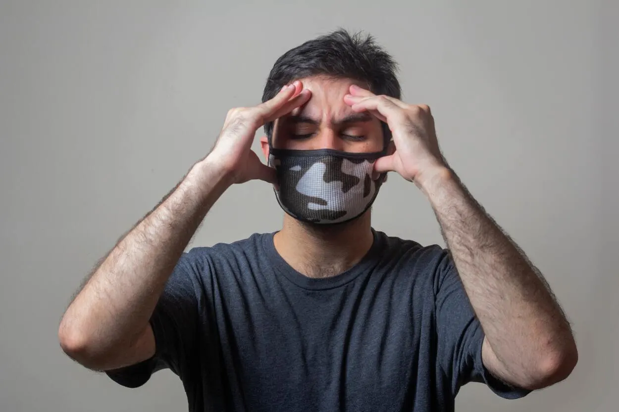 a person having a headache wearing a mask